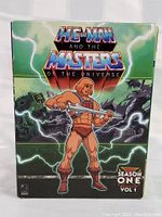 Front view of the He-Man and the Masters of the Universe Season 1 Volume 1 DVD boxed set showing illustrated cover artwork featuring He-Man and vibrant lightning effects.