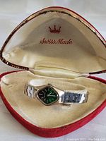 Vintage Bulova watch inside red heart-shaped case with cream interior lining and Swiss Made marking
