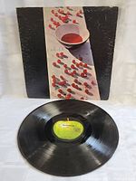 Photo of the vinyl record with visible Apple Records green label and front album cover with distinctive artwork.