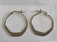 Pair of lightweight sterling silver geometric-shaped hoop earrings on white fabric background showing overall shape and condition.
