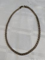 Full view of the 15.5 inch vintage sterling silver thick chain necklace laid flat on a white textured fabric background.