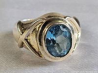 Front view showing the polished sterling silver band and large oval blue sapphire gemstone with faceted cut and natural inclusions.