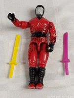 Front view of the GI Joe Ninja action figure with two plastic swords, one yellow and one pink.