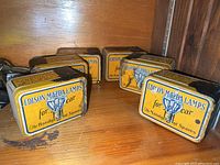 Front view of 6 matching antique Edison Mazda light tins with yellow and black colors and lettering related to car lamps.