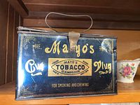 Front view of antique Mayo tobacco lunchbox tin with gold and blue design, metal handle and latch.