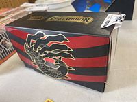 Box showing sides with red stripes and hand graphic design.