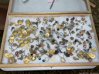 Photo showing a variety of costume jewelry findings including buttons, pendants, earrings, and other small components spread out in a display case.
