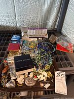 Tray of assorted costume jewelry including boxed Avon pieces, multiple beaded necklaces in blue and green, floral pins, and various earrings.