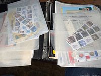 Photo of open binder with many translucent sheets holding multiple sets of unused United Nations stamps including commemoratives and special edition stamps.