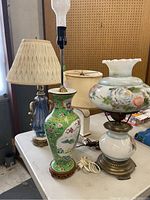 Four lamps grouped on a table showing varied height, bases, and shades for overall lot view.