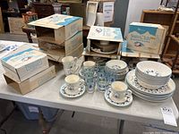 Overview of set on table showing plates, bowls, cups, saucers, glasses and boxes