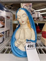 Front view of Mother Mary porcelain vase showing facial features, blue cloak, and praying hands.