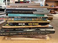Stack of 11 paperback books with titles visible on spines, including poetry, how-to, fiction and non-fiction.