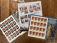 Three sheets of unused vintage postage stamps featuring Lucille Ball, Humphrey Bogart and 1980s movie themes laid out on a wooden surface.