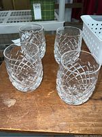 Four Waterford crystal glasses arranged on a wooden surface showing their overall shape and cut patterns.