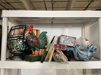 Shelf showing a variety of decorative items including a large rooster statue, baskets, books, and smaller decor pieces