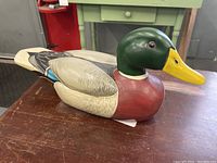 Side view of wooden duck decoy showing painted head, wings, and chest detailing
