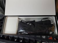 The open box showing black and grey heated socks folded inside with accompanying box for accessories or batteries.