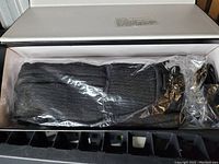 Photo showing the heated socks folded and sealed in plastic inside the original white box with rechargeable battery pack visible.