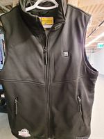Black sleeveless heated vest hanging, showing front zippered pockets and heating control button on chest.