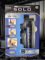 Front of the MicroTouches Solo razor box showing the product in black with a grey SOLO logo, highlighting ability to trim, edge, and shave with one tool, dual-sided blades, and ease of use.