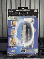 Front view of MicroTouches Solo razor in packaging showing the product and its trimming, edging, and shaving capabilities with one tool.