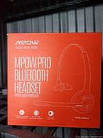 Front of the box showing MPOW Pro Bluetooth Headset model BH015A, highlighting Bluetooth connectivity, 12 hours talk time, ergonomic portable design.