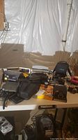 Overview of cameras and accessories laid on table including Nikon Coolpix, Polaroid 210 Land camera, film cameras, and accessories