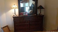 Front view of the 9 drawer wooden dresser showing antique-style metal handles and overall condition with some scratches.