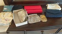 Photo showing set of assorted vintage handkerchiefs with embroidery and lace, several evening bags including metallic mesh bags and handwoven style bags