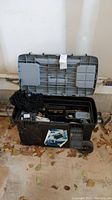 Plastic black and gray rolling tool cart open showing tools and locks inside