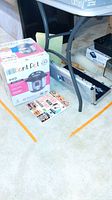 Photo showing the boxed Instant Pot Duo, BBQ tool set in metal case on floor under table.