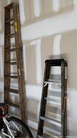 Wooden Keller stepladder (9 ft) alongside the Werner fiberglass stepladder (5 ft) against a wall, showing relative heights and material differences.