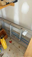 Aluminum ladder laid horizontally against wall, showing metal rails and multiple rungs, and circular level indicators embedded in rails.