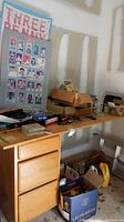 View of posters including Metropolitan Museum baseball cards and Three Penny Opera poster among assorted boxes and tools on a wooden desk.