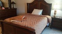 Front view of queen bed frame with carved headboard and footboard, linens on mattress