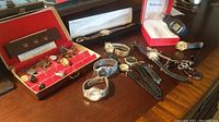 Overview: eight wristwatches, Style & Co. watch in box, watch in black box, red velvet case with cufflinks and tie tacks on wooden table