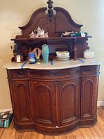 Full front view of antique wood sideboard buffet with white marble top, displaying intricate carved wood backboard and curved cabinet doors.