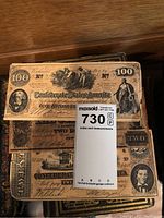 Top view of stacked antique Confederate States currency notes with 100 and 2 dollar denominations visible, showing detailed engravings and signatures.
