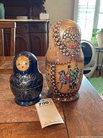 Two largest dolls placed upright side-by-side on a wooden table, showing the color and design difference of both nesting doll sets.