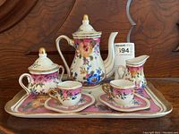 Full view of child's Limoges China tea set displayed on tray including teapot, sugar bowl, creamer, two teacups with saucers