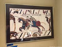 Framed historical print showing knights on horseback and animals with a medieval style, part of Bayeux Tapestry reproduction.