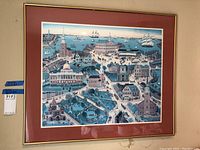 Framed Marie Fox print showing detailed aerial perspective of Boston in the 1700s with ships, buildings, and people, matted in red and framed in gold-tone frame.