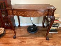 Photo of full front view of the vintage writing desk, showing curved legs with claw feet and ornate inlay detail on apron and top.