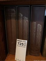 Three vintage books in brown slipcases showing gold embossed architectural column designs and title text 'The Decline and Fall of the Roman Empire' on spines.
