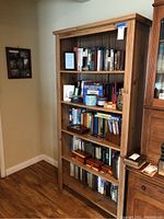 Full view of wooden bookcase filled with various books and decorative items.