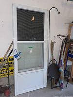 Front view of one aluminum screen door showing white frame, black mesh screen on upper portion, and solid panel below.