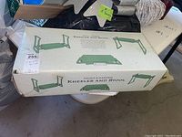 Photo of the unopened box showing Emma's Garden Kneeler and Stool by Restoration Hardware with illustrations of the product in use and brand names.