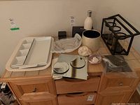 Overview of the diffuser, ceramic platters, candle holder, shells, vase, and mirrored trays placed on wooden furniture.