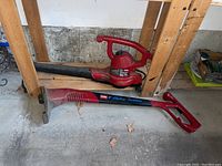 Photo showing the Toro electric leaf blower and Toro 9 electric trimmer on a garage floor with wooden framing in the background.